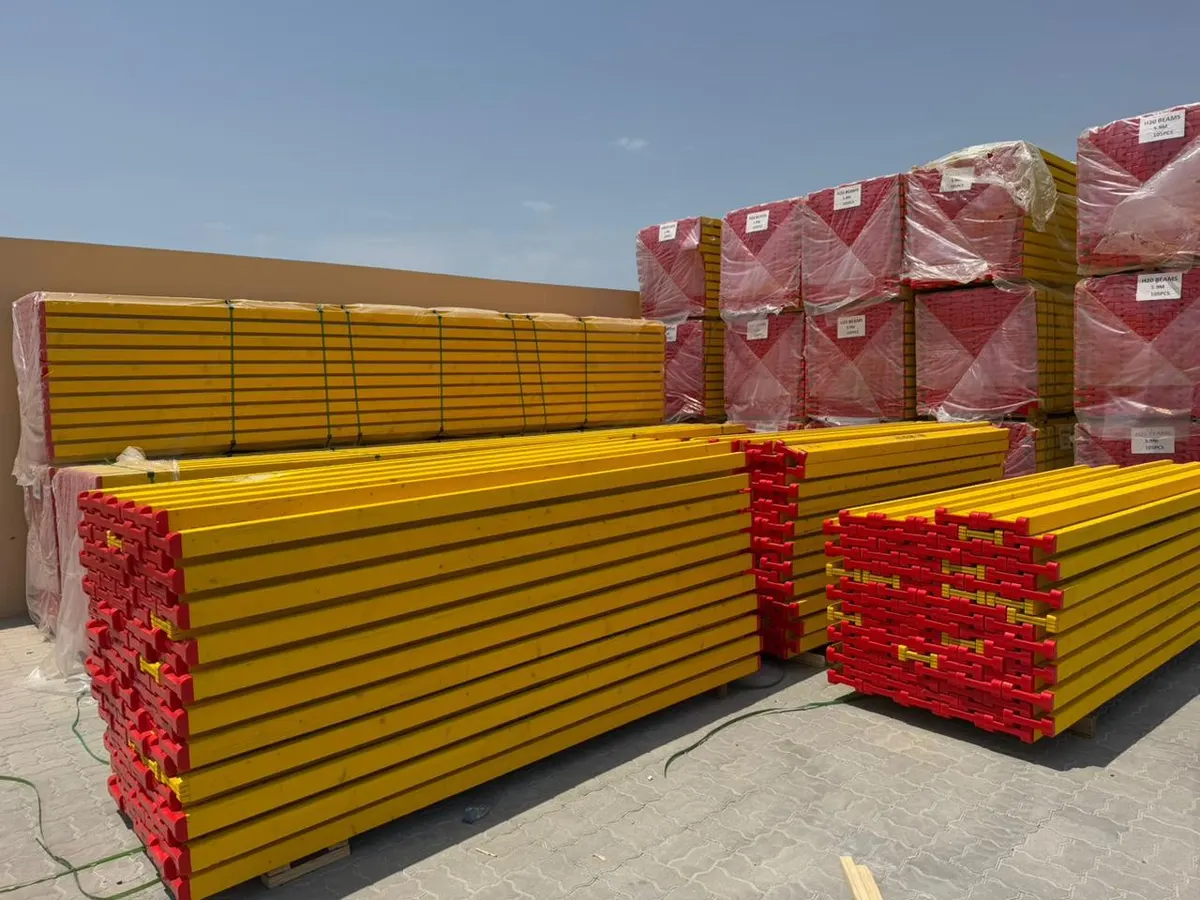 Yellow H20 timber formwork beams with red end caps, stacked in the yard